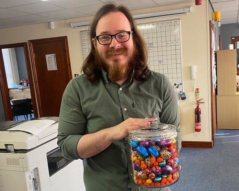 Joshua Kerry holding a jar of sweets in an office