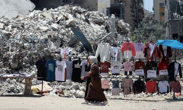 A Palestinian street vendor sells clothes near the rubble of al-Shuruq tower in Gaza city.