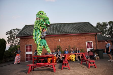 A dancer in a green lion costume dances on a red table