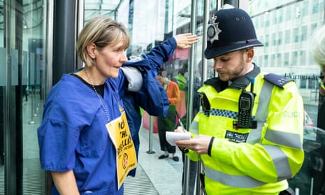 Sarah Benn, a GP from Birmingham, talks to a police officer after glueing her hand to the entrance of the Department of Business, Energy and Industrial Strategy in London.