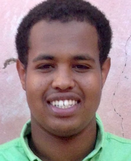 A cheerful teenaged boy of Somali heritage in a green collared shirt smiles at the camera