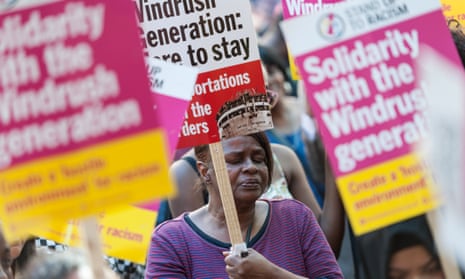 A demonstrator with a sign reading ‘Windrush generation: here to stay’