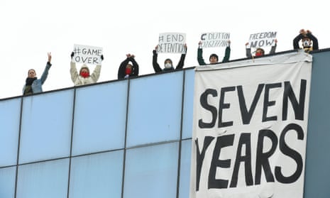 people with placards and large banner on a roof