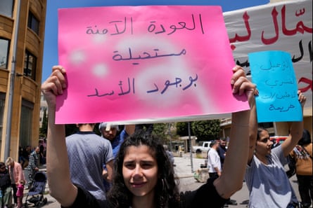 A young female protester holds a sign in Arabic during a street protest 