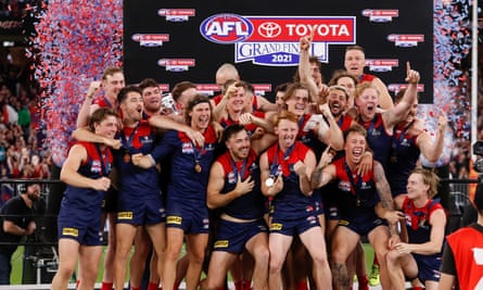 Demons players celebrate on stage after the grand final as blue and red confetti flies around them