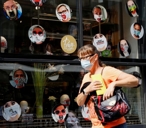 A woman passes by a shop window with masks on display in Vienna, Austria.