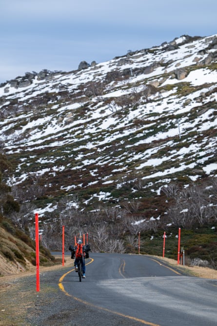 A cyclist carrying back-country skis rides up Kosciuszko Rd towards Charlotte Pass from Perisher Blue Ski Resort, NSW.