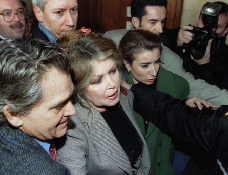 Brigitte Bardot, centre, is led into a court in Paris surrounded by paparazzi