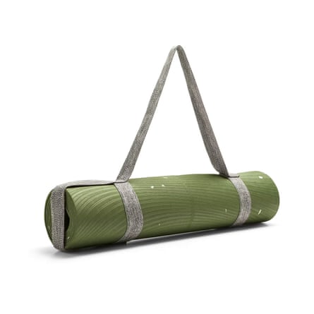 A rolled up green grippy yoga mat in its grey net shoulder carrier.