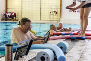 Patients with musculoskeletal problems use waterproof tablets during a Good Boost aqua therapy exercise session