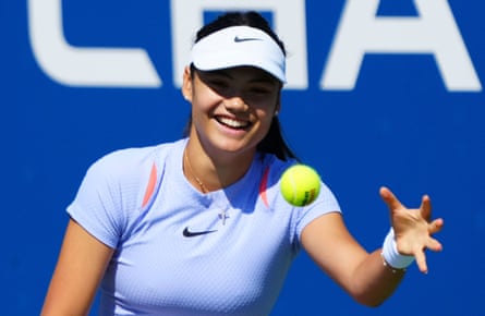 Emma Raducanu smiles as she catches a tennis ball one-handed.