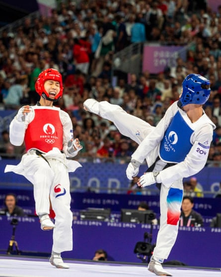 Taejoon Park of Korea reels from a kick by Cyrian Ravet of France before going on to win their mens 58kg taekwondo quarter-final at the Grand Palais.  