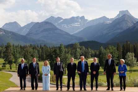 a row of people posing for a picture in front of mountains