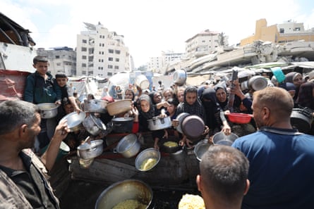 Palestinians queueing up with pots and pans at a food distribution centre