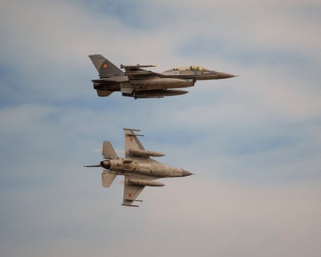Two F-16 fighter jets fly in formation against a cloudy sky