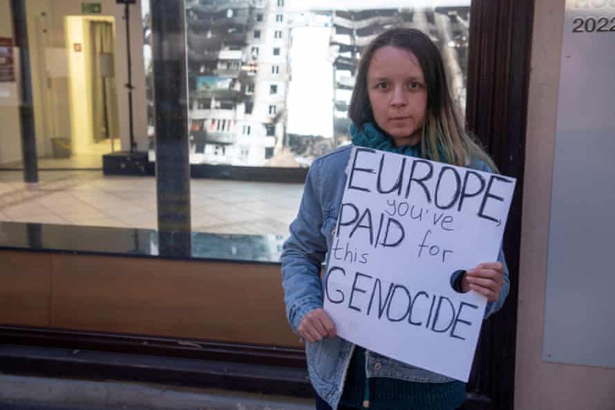 A woman displays a poster in front of the Russian War Crimes House in Davos.