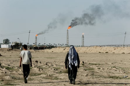 People walk near farmland by the Zubair oil field.