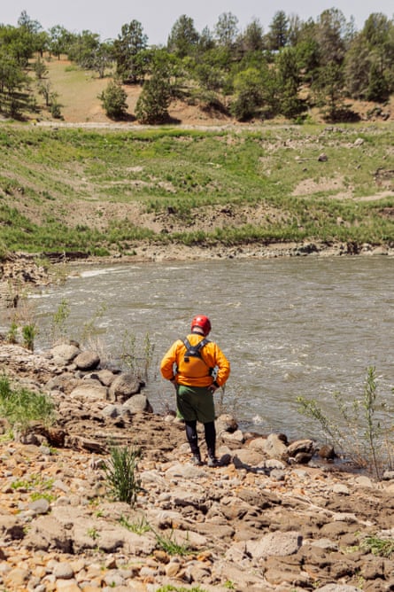 A man stands at the edge of a river.