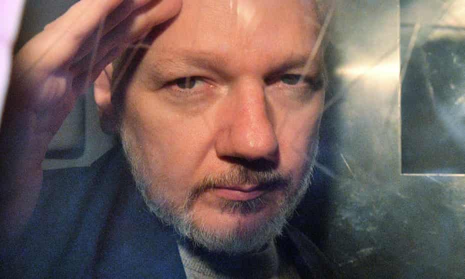Julian Assange gestures from the window of a prison van as he is driven out of a London court in May 2019