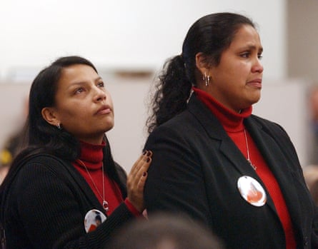 two women wearing black jackets over red turtlenecks with badges on them