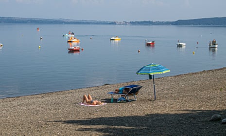 People sunbathing on a deserted beach by Lake Bracciano, Italy