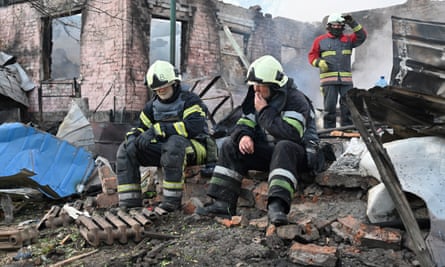 A pair of firefighters sit amid rubble