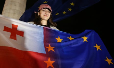 A demonstrator holds the Georgian national and EU flags during an opposition protest in Tblisi on 3 May.