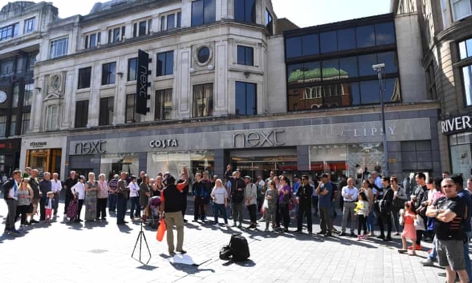Shoppers watch a street entertainer in Liverpool