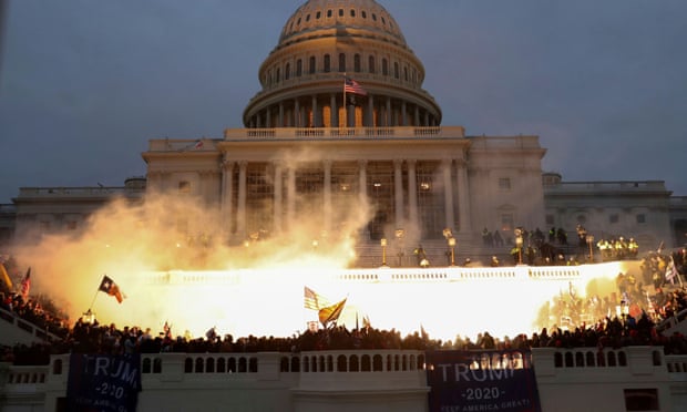 An explosion caused by a police munition is seen in front of the Capitol while supporters of Donald Trump storm the building.