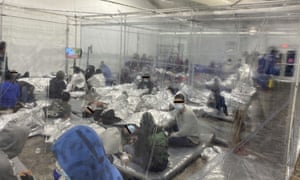 Migrants crowd a room with walls of plastic sheeting in Donna, Texas.