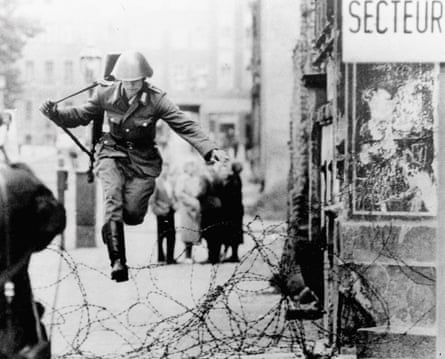 East German soldier Hans Conrad Schumann leaps over a barbed wire barricade at the Bernauer Street sector into West Berlin in August 1961