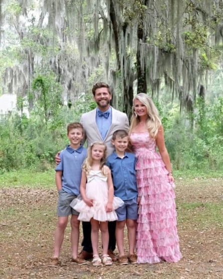 A man, a woman and three children pose under a large, moss-covered tree