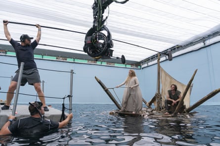 Morfydd Clark and Charlie Vickers surrounded by crew in a water tank