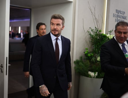 he is smartly dressed in a dark suit and tie.