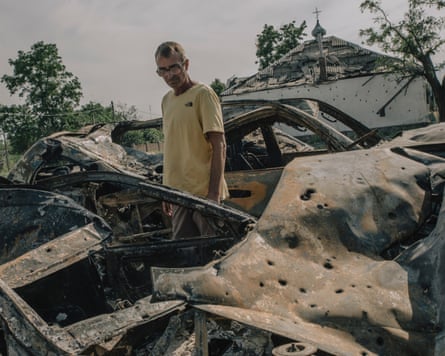 Middle-aged man in a yellow T-shirt next to burned out cars
