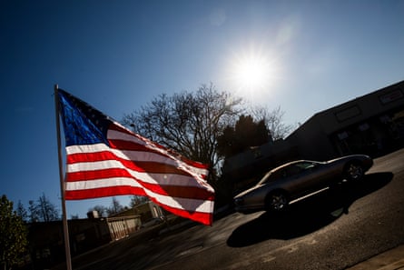 A car drives past, an American flag in the foreground