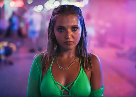 A woman in a bright green bikini on the street, with a pink-lit background