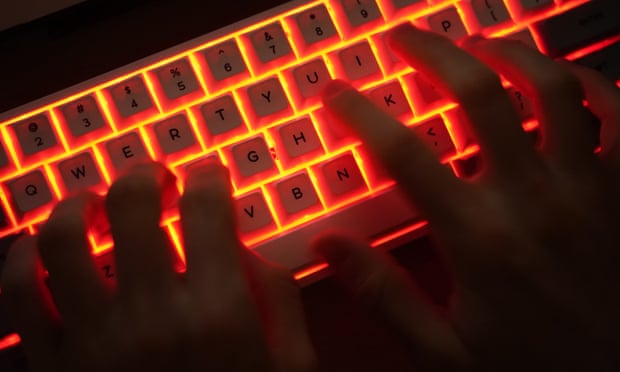 Stock photo of man typing on an illuminated computer keyboard