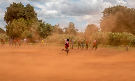 Young boys play a game of soccer on a dusty playing field in Kuwadzana.