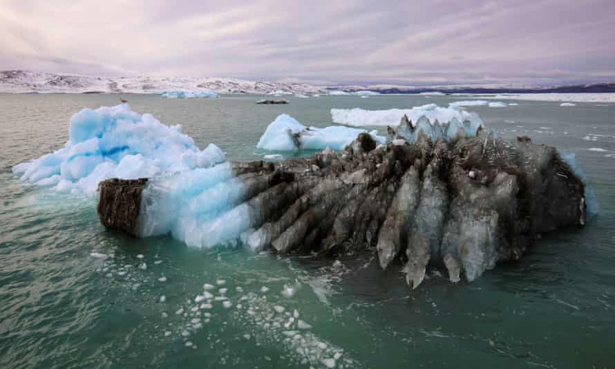 An iceberg with half of the ice black with what looks like soot