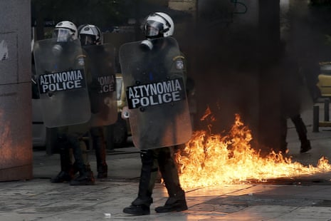 Greek riot police stand by fires caused by petrol bombs thrown by youths following brief clashes between police and protesters during a protest marking a 24-hour strike in Athens, Greece, December 3, 2015. Striking Greek workers will take to the streets on Thursday, disrupting transport, shutting schools and keeping ships docked at port in the second major protest against planned pension cuts in three weeks. REUTERS/Alkis Konstantinidis