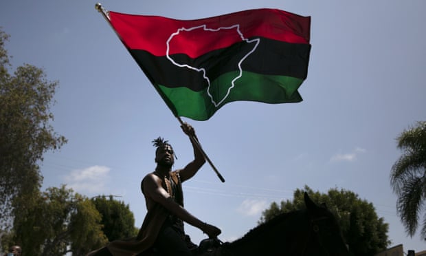 man waves flag with red, black and green bars and outline of africa