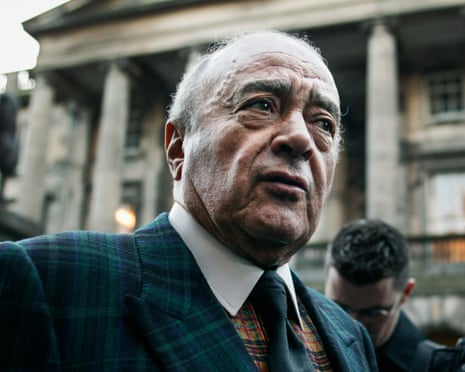 Fayed in a dark plaid suit looks upward outside a grand columned building