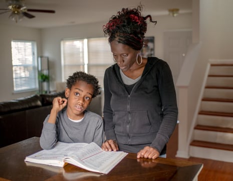 Joshua, a boy on the autism spectrum, photographed with his mother, Danyale, looking at a book on a table, in 2018