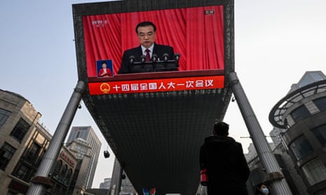 An outdoor screen shows live news coverage of China’s premier, Li Keqiang, at the opening session of the National People's Congress