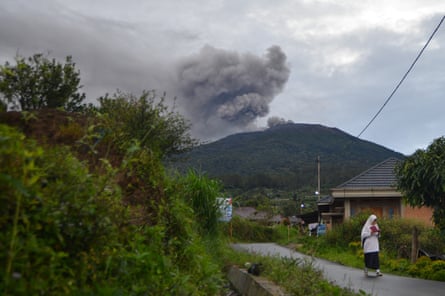 Um estudante passa enquanto o vulcão do Monte Merapi vomita cinzas vulcânicas