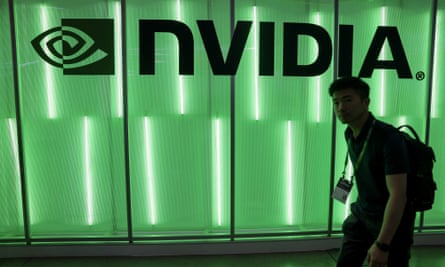 A person walks past a Nvidia logo lit by green neon lights