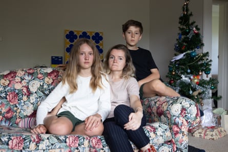 Mariia Mykytiuk and Anastasia Prokopchuk and Kyrylo Prokopchuk sitting on a couch with a Christmas tree behind them