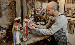 Craftsman Marco Ferrigno works on Christmas nativity figurines, including the three wise men showing their Covid-19 health passes.