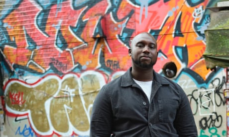 Caleb Azumah Nelson standing in front of a graffited wall